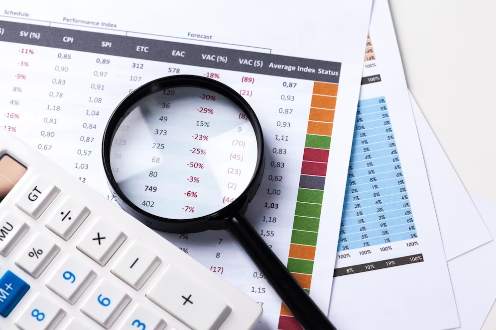 Photo of a magnifying glass, calculator, and papers with data placed together